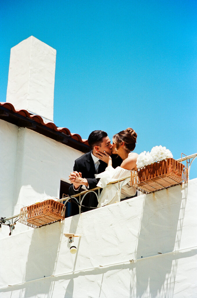 hybrid photography film photo of a bride and groom kissing on a balcony