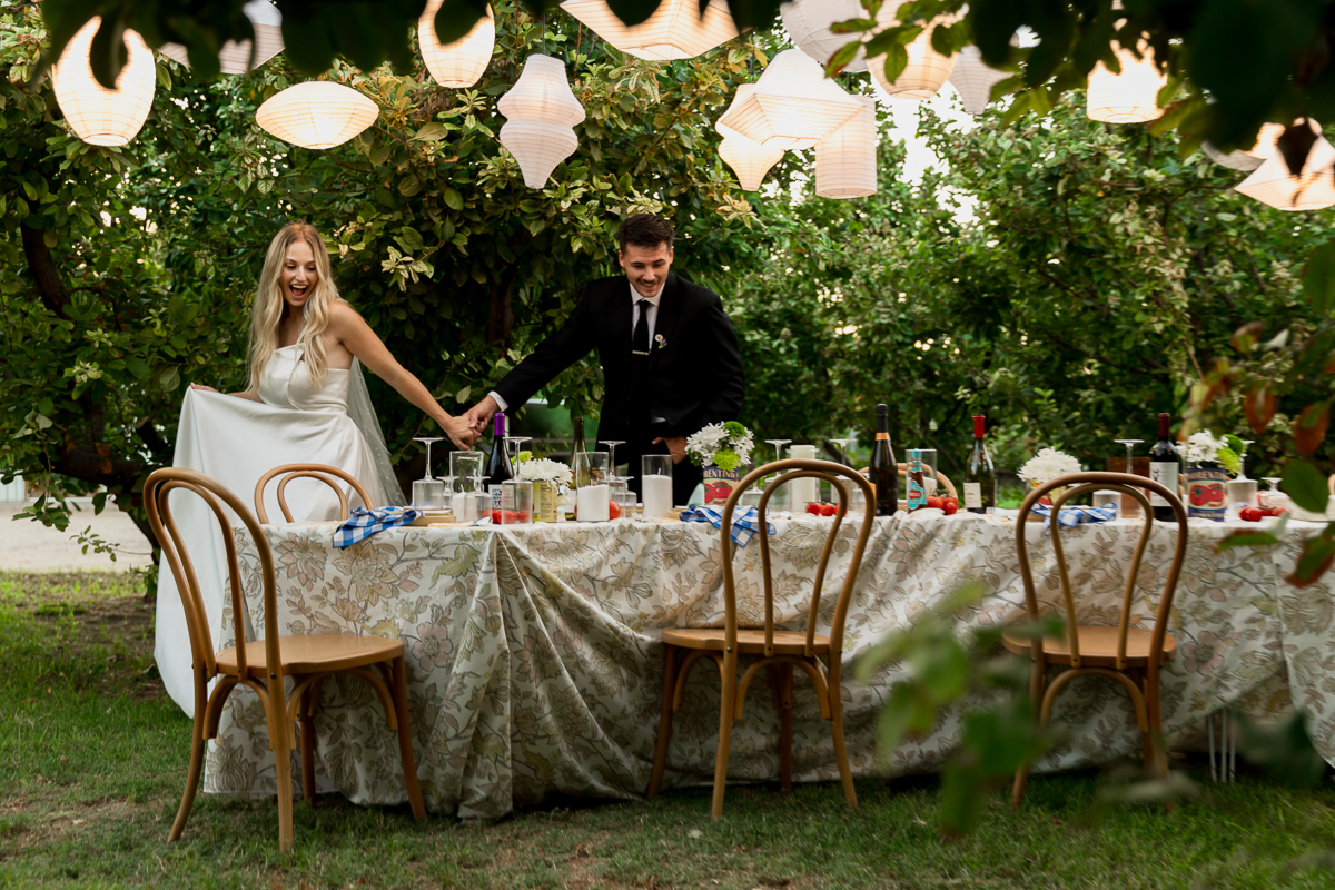 bride and groom walking around their wedding reception table set up and seeing it for the first time